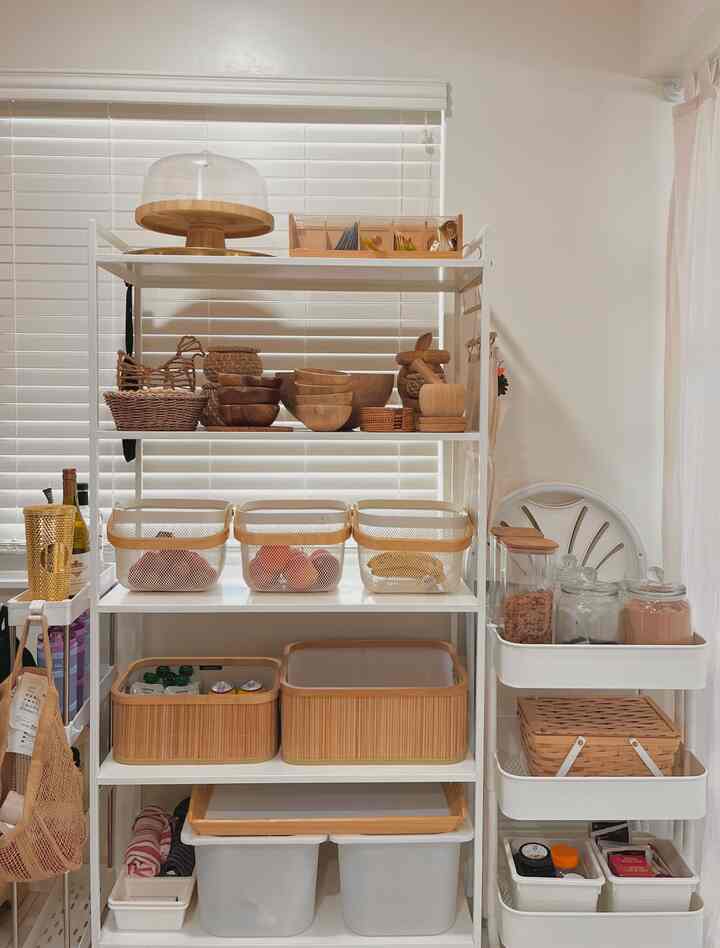 White and beige toned kitchen storage with neatly organized wooden and rattan items creating a clean, natural look
