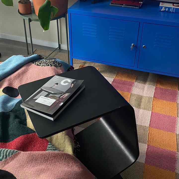 Modern living room featuring a blue cabinet, black side table, patterned rug, and a plant for natural touch