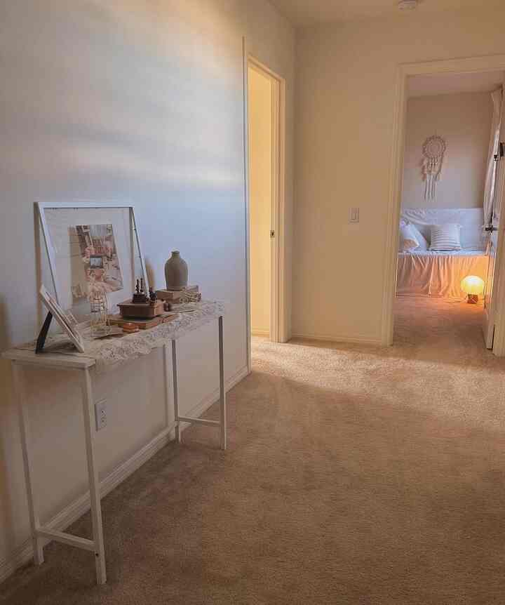 White and beige toned hallway featuring a slim console table with decor, creating a cozy and simple atmosphere