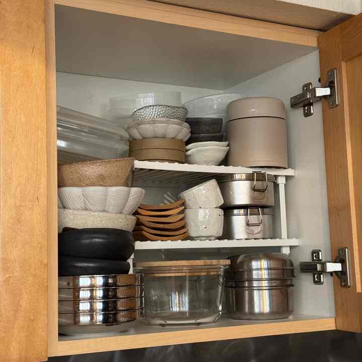Natural-tone kitchen cabinet interior with neatly organized plates and bowls showcasing efficient storage