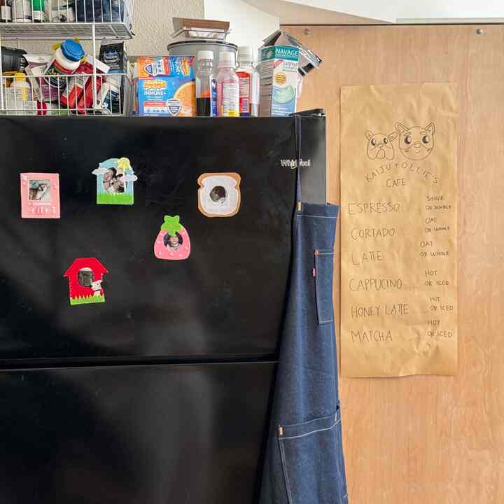 Black fridge with denim apron and handmade coffee menu in a cozy loft-style kitchen space