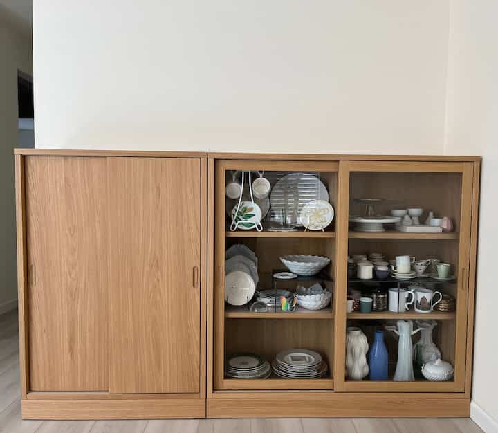 Natural wood-toned kitchen cabinet showcasing organized assorted plates and glassware in tidy storage