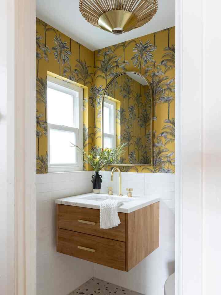 Bright modern powder room with yellow palm wallpaper and wood-tone storage cabinet