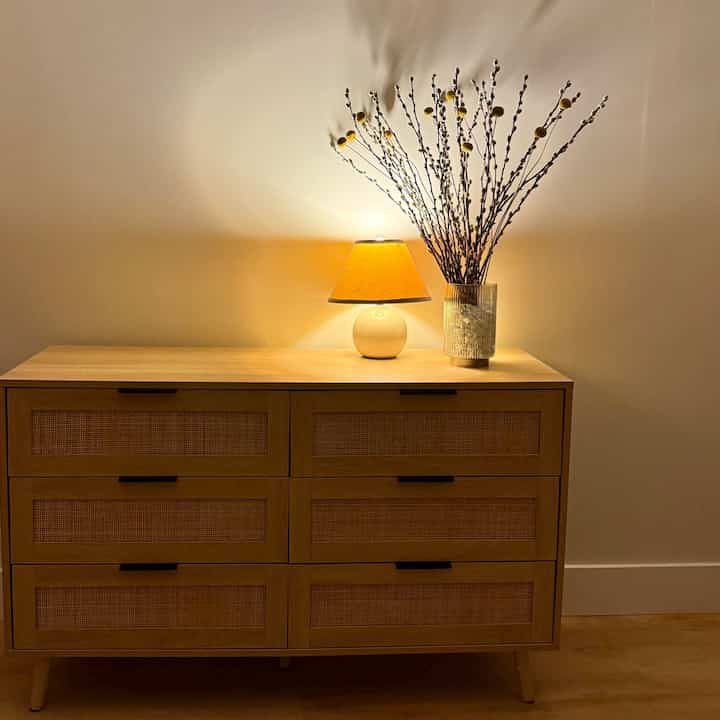 Cozy space with brown mid-century modern chest of drawers illuminated by warm yellow table lamp lighting