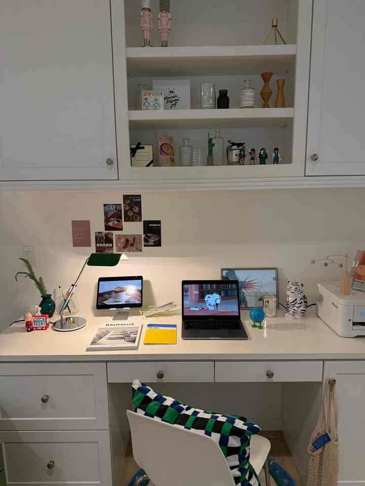 White-toned home office space featuring a desk, chair, tablet, and laptop in a tidy workspace setup