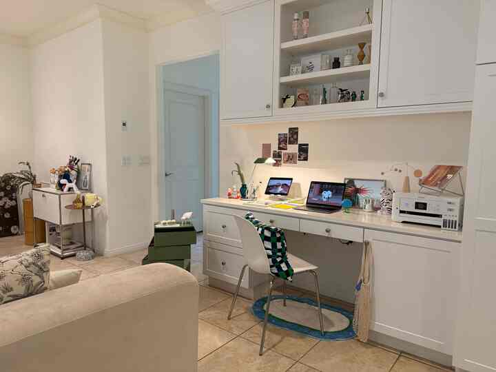White-toned living and home office space with mid-century modern style desk and storage cabinets in a clean interior