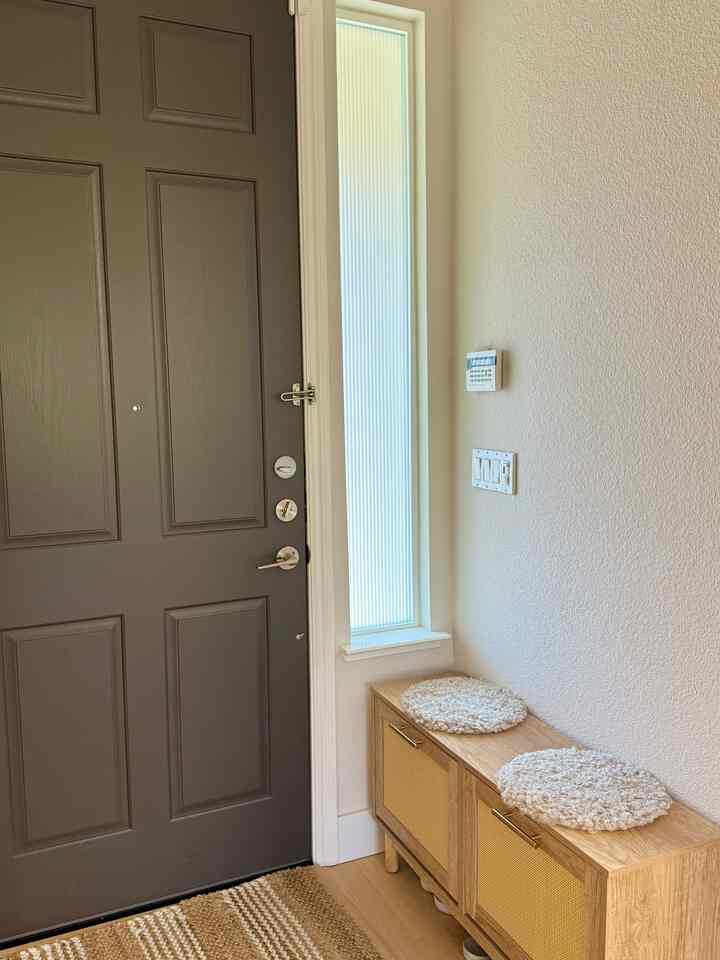 Beige walls and wood-tone storage cabinet in a cozy entrance space, with a front door and neat decor