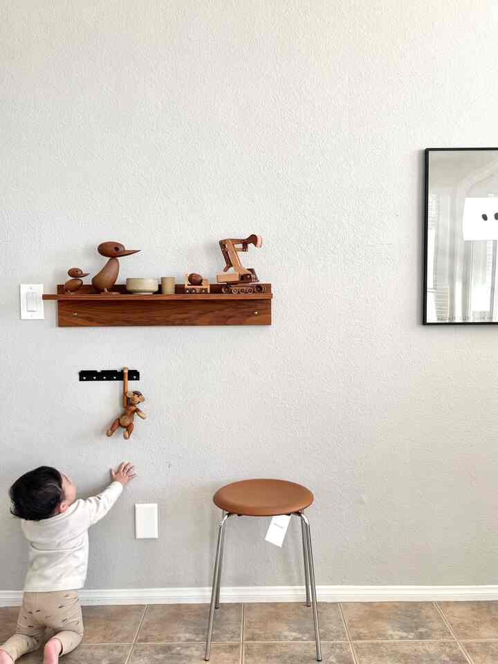 Warm natural wood tone space with wall shelf, baby, and wooden toys