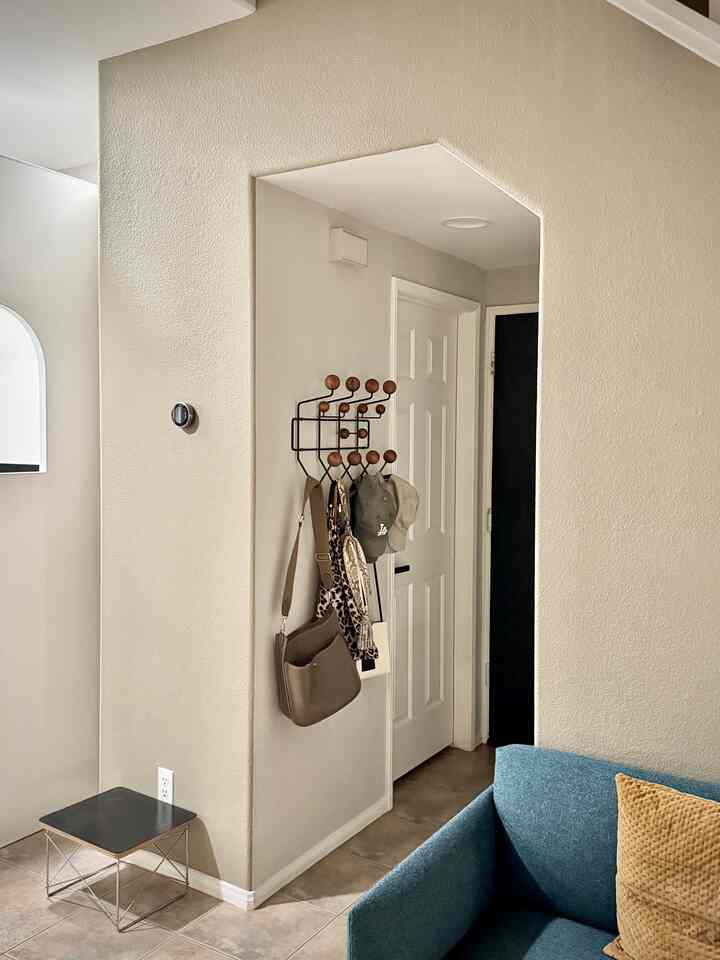 Beige-toned entrance area featuring blue sofa and black wall decor with wooden hooks
