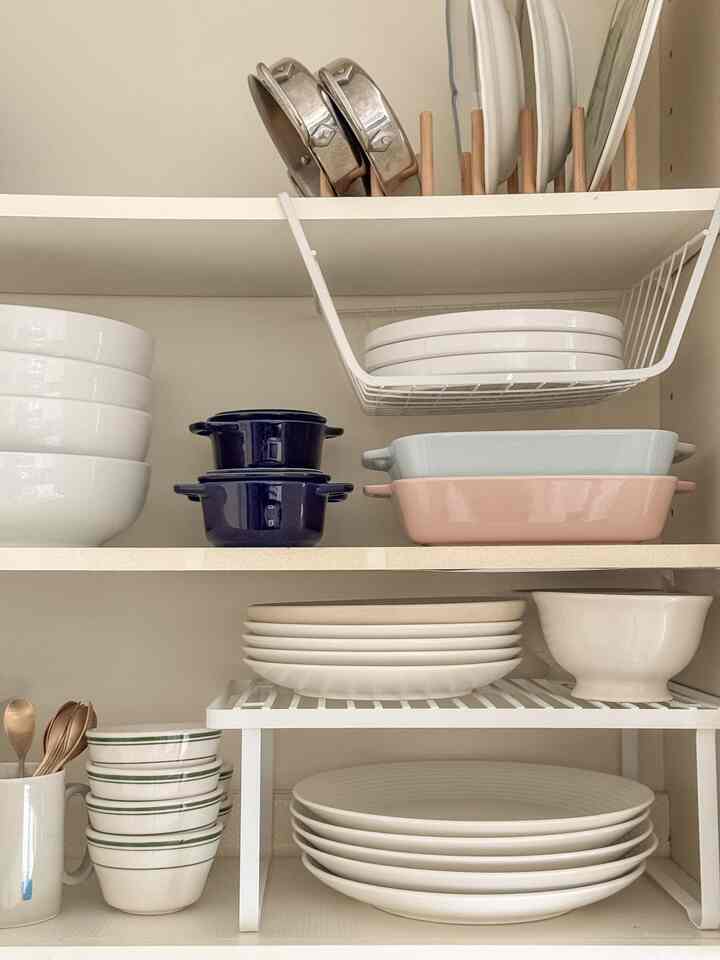 White and wood tone kitchen shelves featuring neatly organized plates and bowls with a clean and minimal atmosphere