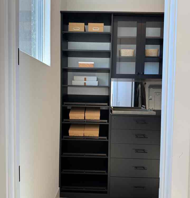 A compact space featuring a black wardrobe with decorative storage boxes showcasing neat storage organization