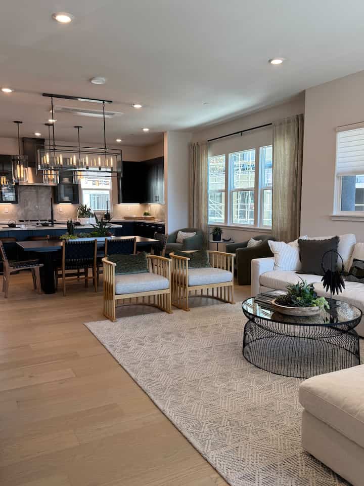 White and natural color toned living and dining area featuring modern furniture and an attractive coffee table in a spacious, cozy setting
