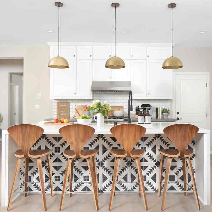 White kitchen space featuring wooden bar stools and gold pendant lights in a mid-century modern style interior