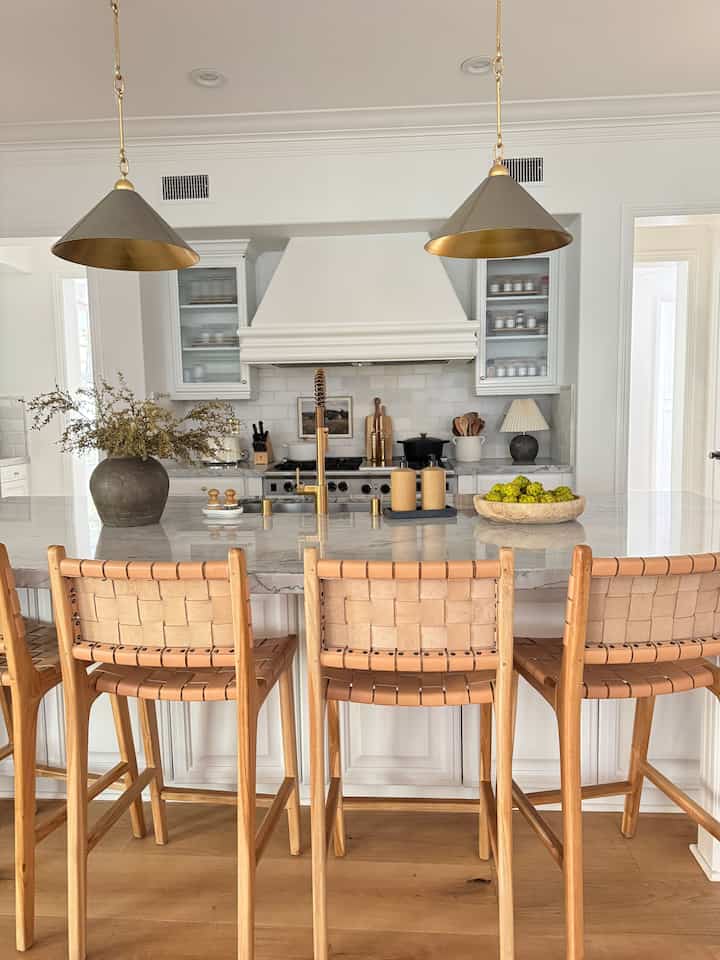 Natural modern style kitchen featuring wooden stools and white kitchen island with a warm, inviting atmosphere
