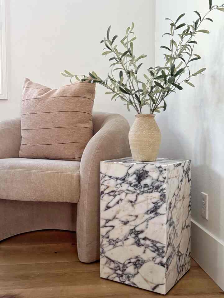 Natural color and wood tone bedroom corner featuring a beige armchair and marble side table creating a cozy atmosphere.