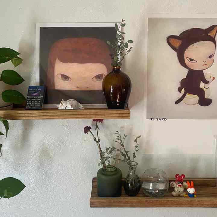 Japandi-style wall interior with natural wood tone shelves featuring brown and green vases and art prints