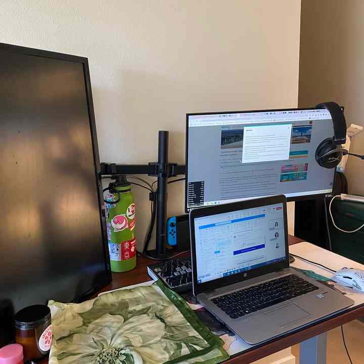 Brown wooden desk featuring white laptop and dual monitors in a simple home office setup