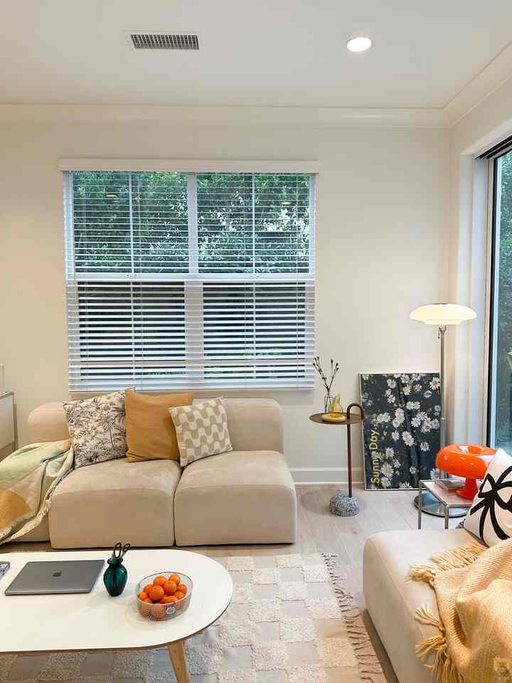 Bright beige and white toned living room featuring soft sofas, side table, and cozy natural light ambiance