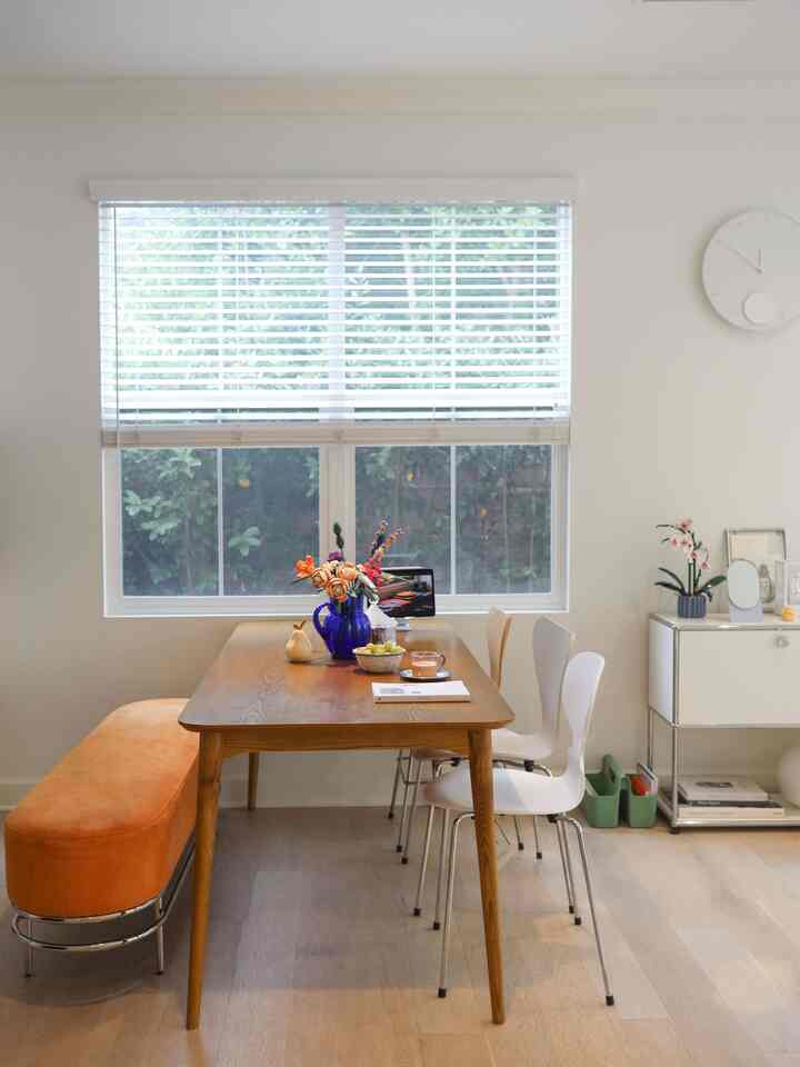 White and orange toned dining room featuring a Mid-Century Modern wooden dining table and chairs with a cozy atmosphere