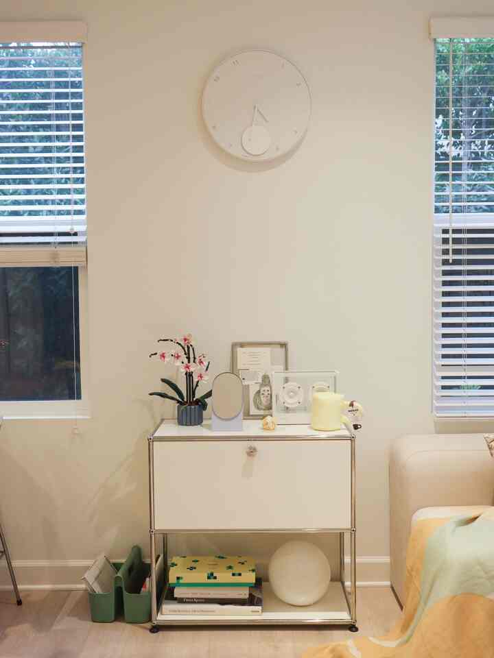 White and natural toned living room featuring a storage cabinet and wall clock centrally placed with a simple atmosphere