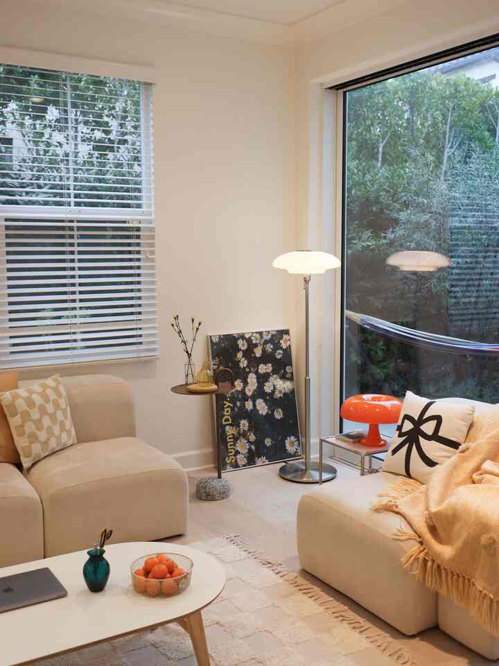 Beige and white toned living room featuring mid-century modern furniture and floor lamp with a cozy and natural atmosphere