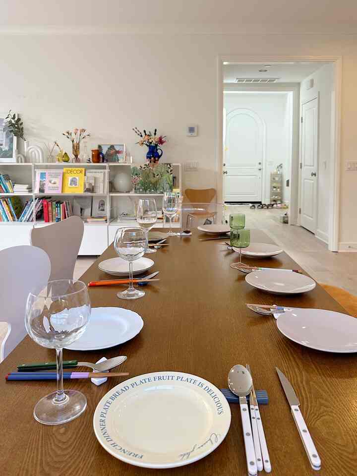 Modern dining room with white walls and brown wooden dining table featuring chairs and tableware in a clean setting