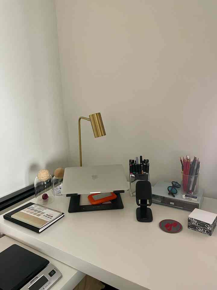 White and gold toned home office workspace featuring a desk with a laptop stand and gold desk lamp in a simple, organized setting