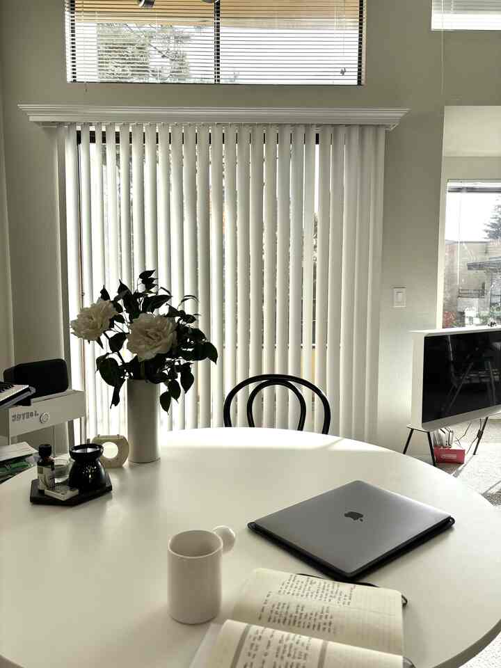 White and black toned living room home office featuring a round table with laptop and coffee cup in a minimal setting