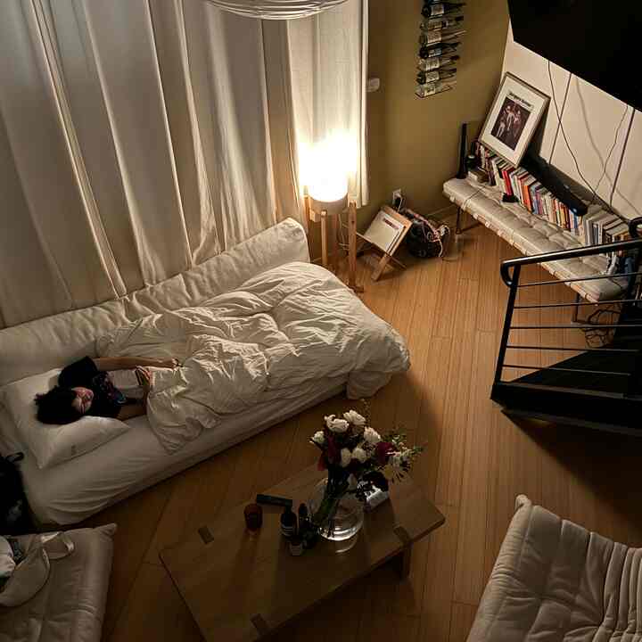 Cozy loft living room with warm wood tones and white accents, featuring a sofa bed and coffee table as focal points