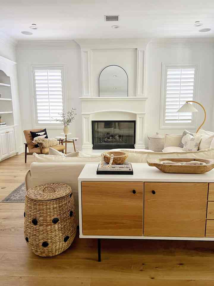 White and brown toned living room featuring a large sofa, armchair, and arched fireplace in a clean natural modern setting