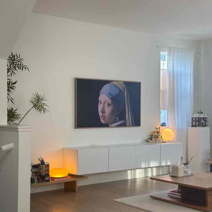 Bright white and natural color tone living room featuring a large framed artwork and minimalist furniture with cozy atmosphere