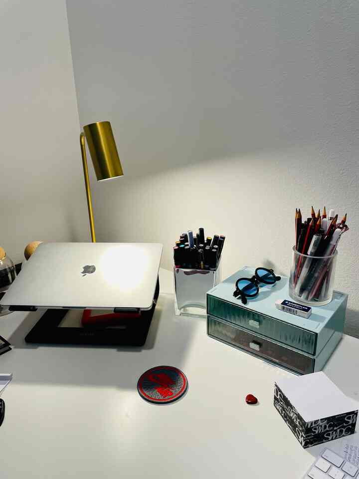 White-toned home office desk featuring gold desk lamp and organized drawer, creating a clean workspace atmosphere