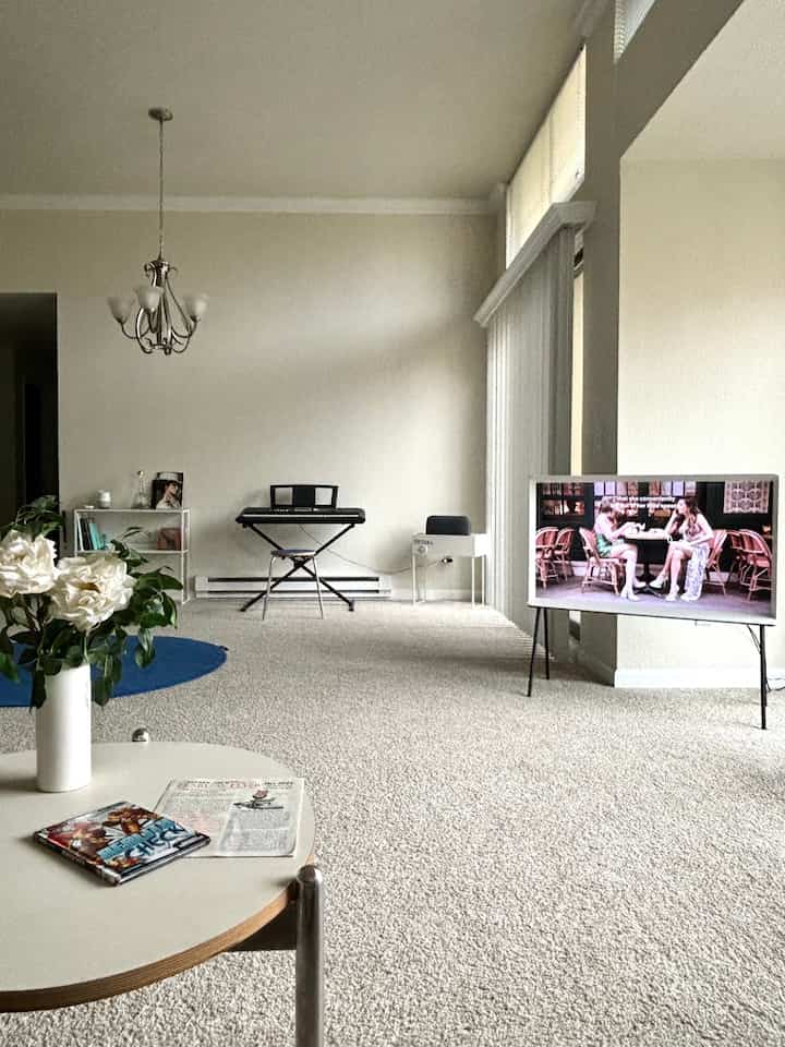 A white and minimal-toned living room featuring a piano centered back and a TV stand on the right, arranged in a clean space