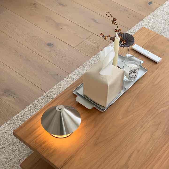 Warm wood-tone living room featuring a wooden coffee table with a lit table lamp and candles on a tray, creating a simple natural atmosphere