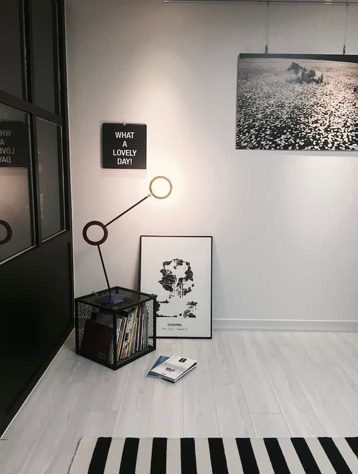 Monotone living room corner with white walls and floor, black door frame and metal cube storage, featuring a minimalist and clean interior design