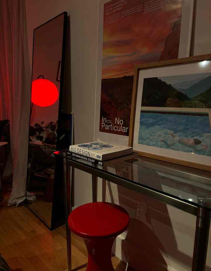 A modern space with red lighting and a red stool, featuring a glass table and art posters in a calm mood