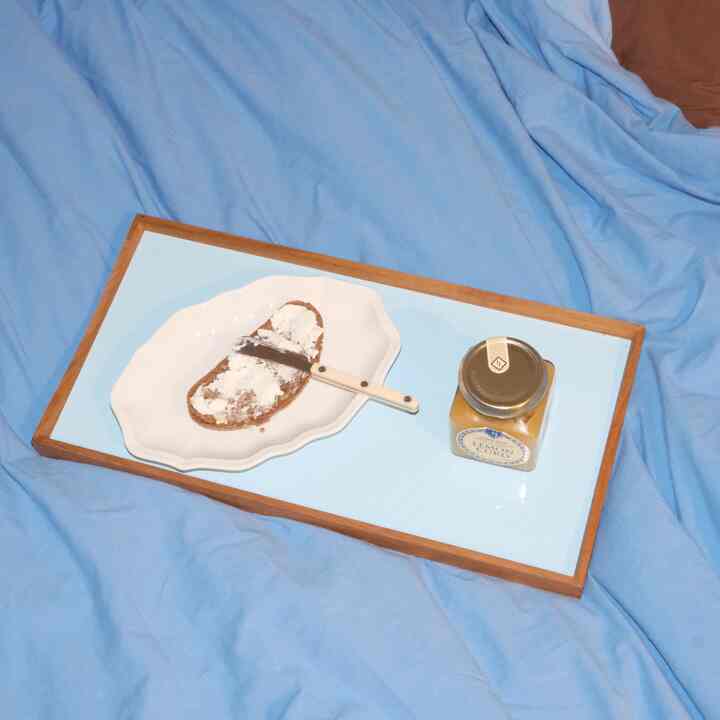 Bright blue-toned bedroom featuring a tray with cutlery and bread centrally, creating a cozy breakfast setting