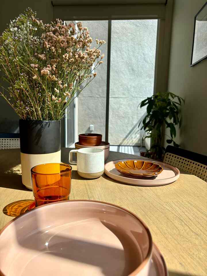 Natural tones with orange accents in dining room featuring a table setting and floral arrangement creating a warm atmosphere