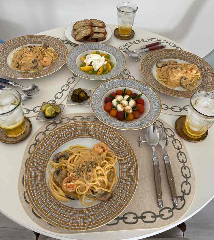 White tone round dining table featuring gold patterned plates and drinks in a clean and elegant dining setup