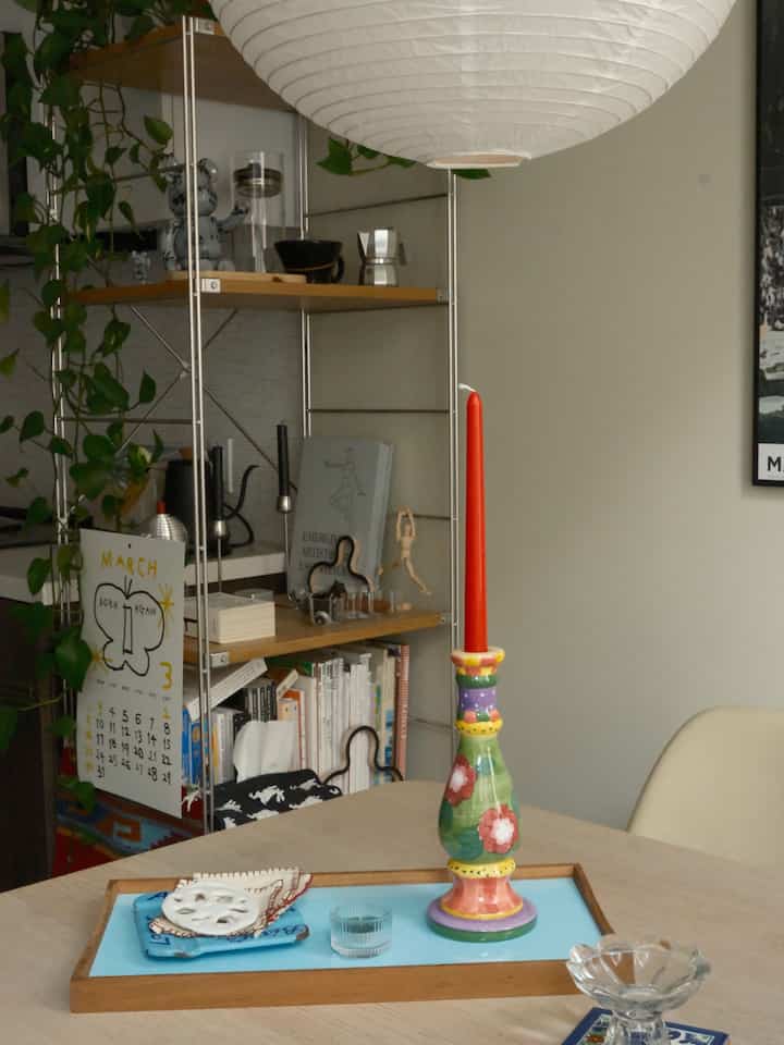 White and wood tone dining room featuring a colorful candle and tray creating a natural and cozy atmosphere
