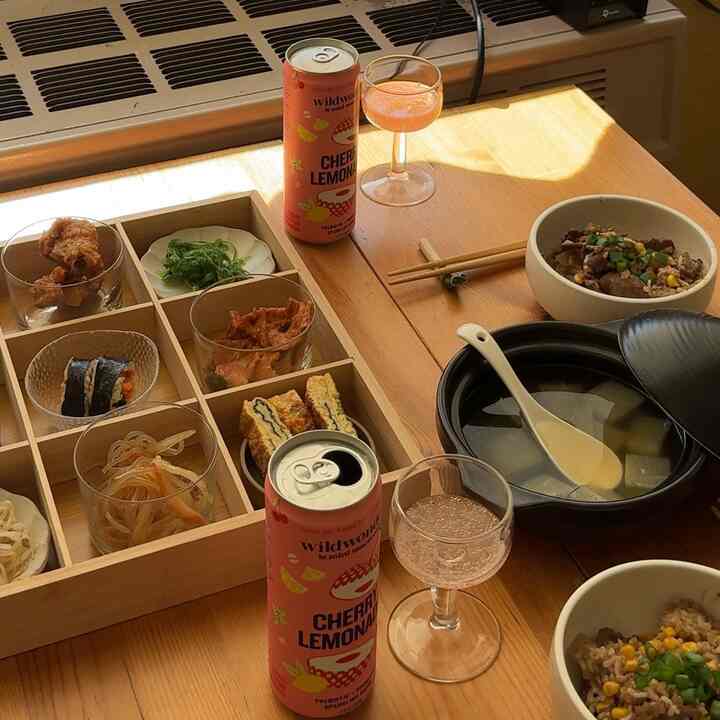 Cozy Japandi-style loft dining table featuring natural wood tones with assorted bowls and drinks arranged neatly