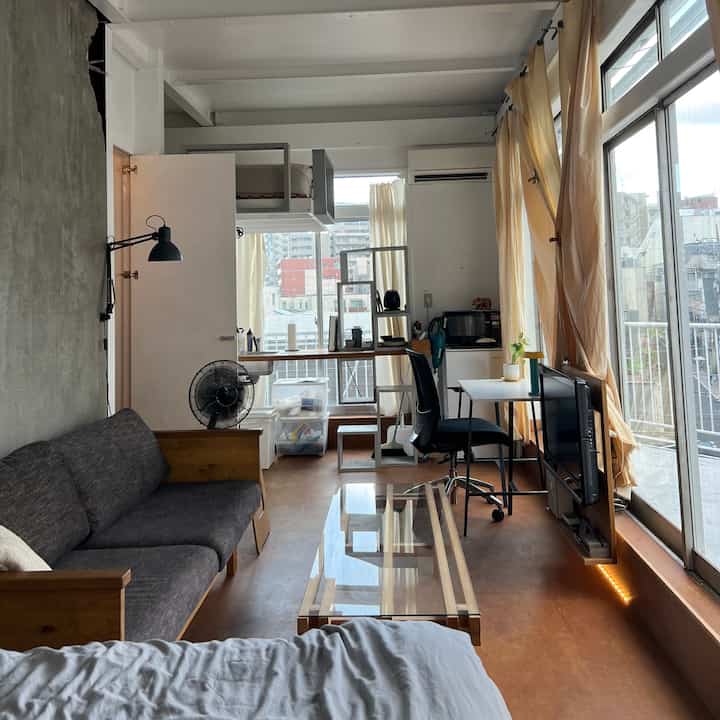 Natural wood tones and white color blend in a studio living room and home office space with a bright, cozy atmosphere