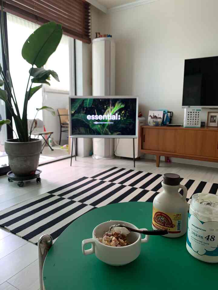 White and black toned living room featuring a large green dining table and plant, creating a modern home cafe atmosphere