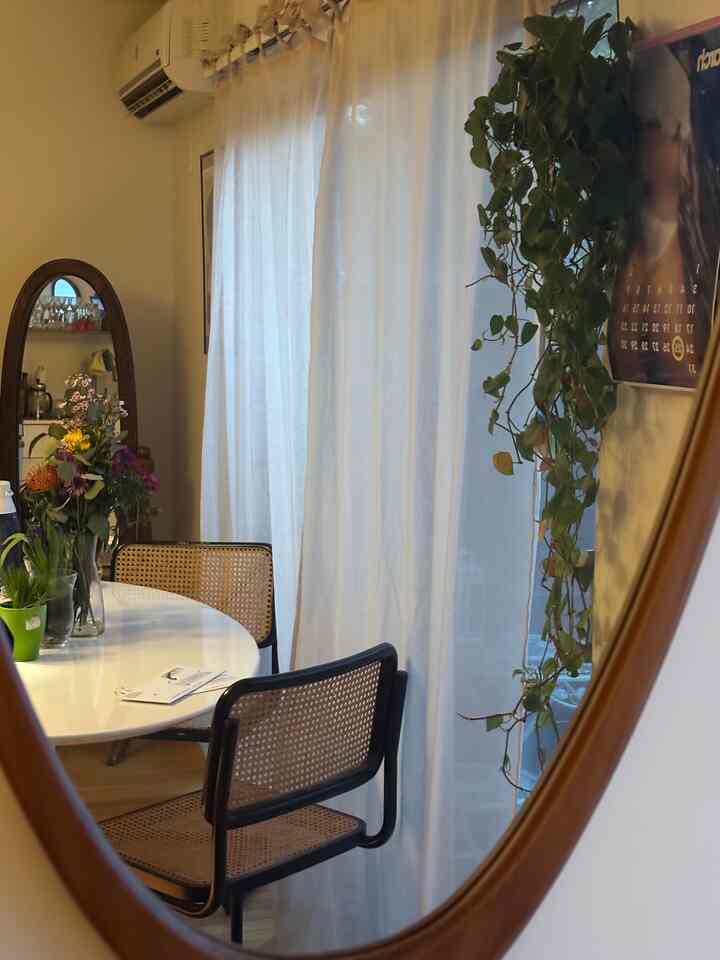 White and wood tone dining room featuring wooden chairs and a large oval mirror creating a warm atmosphere