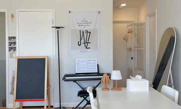 White and wood tone combined living and entrance space featuring a piano and simple furniture, creating a minimalist atmosphere