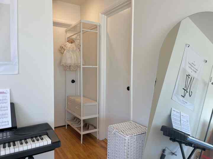 White and natural color toned small entrance featuring a mirror and coat rack with tidy storage ideas