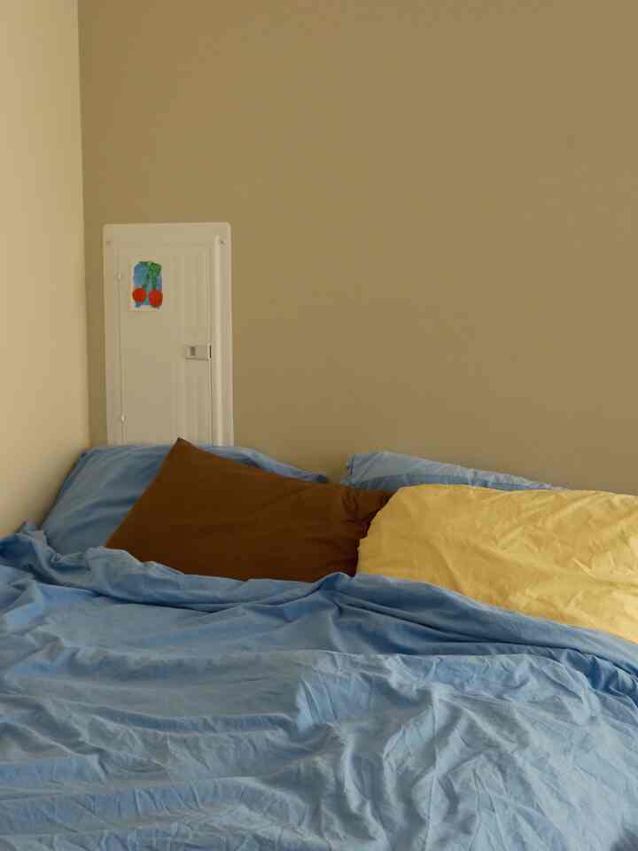 Beige-walled bedroom featuring a cozy bed with blue bedding and warm pillow tones