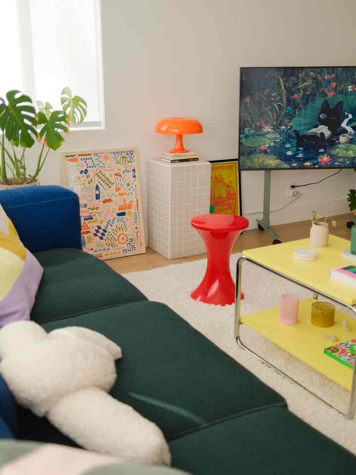Natural tones with red and yellow accents in a living room featuring a sofa, stool, and table lamp creating a modern atmosphere
