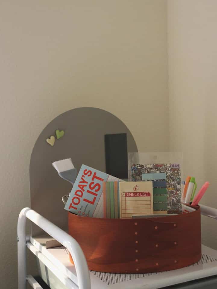 White-toned home office space featuring a wood-tone shaker tray organizing stationery, creating a neat workspace