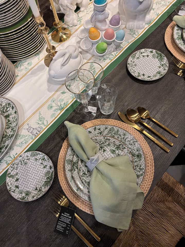 Dining room table setting in green and gold tones, featuring intricate plates and decorative objets for an elegant ambiance